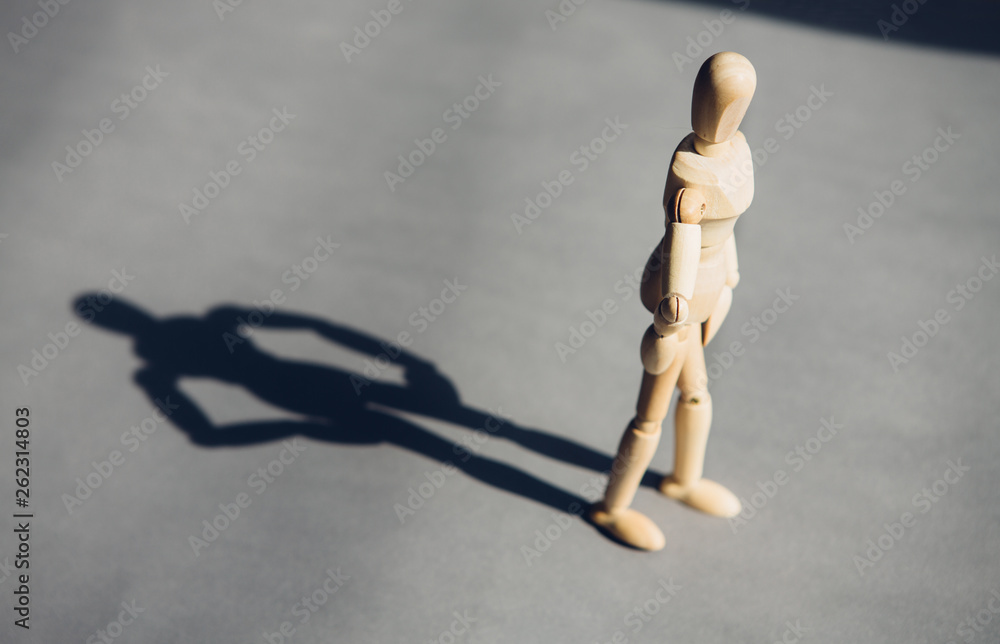 wooden man stands in front of the sun behind him, his shadow. The concept of personality, leadership. wooden man stands in front of the sun behind him, his shadow. The concept of personality, leadership.
