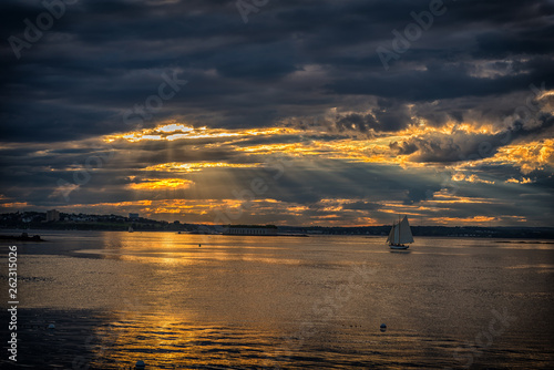 Beautiful Sunset over Portland, Maine with gorgeous clouds and light streaming down on Casco Bay and a windjammer sailing ship.
