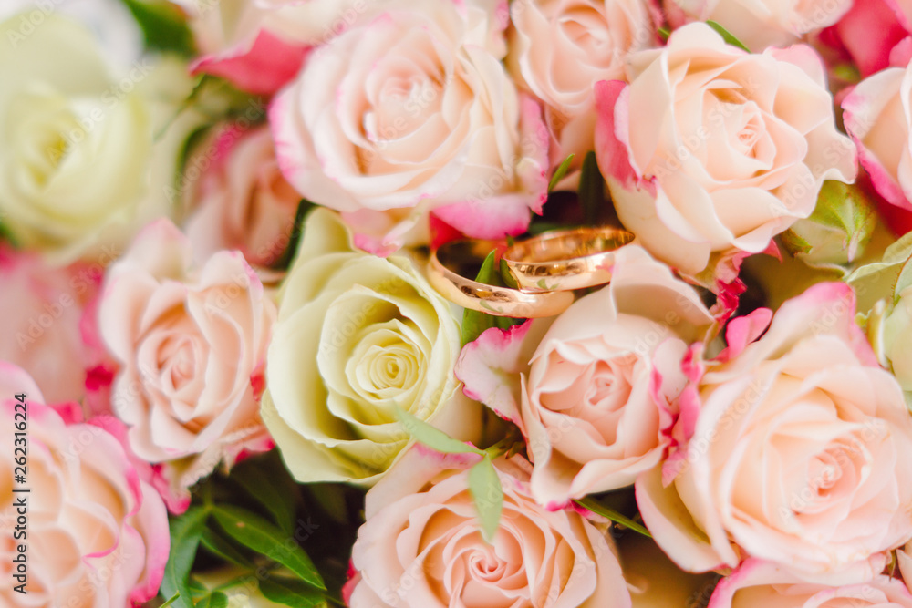 Wedding rings on bridal bouquet background. Gentle