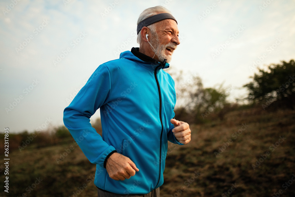 Cheerful mature athletic man running in nature.