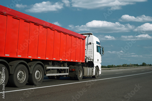 The red truck is going up the road. Cargo transportation concept.