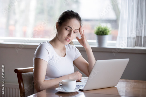 Young beautiful woman having headache working on computer at home