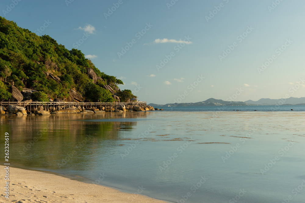 White sandy tropical beach with calm wave and blue lagoon on sunny day
