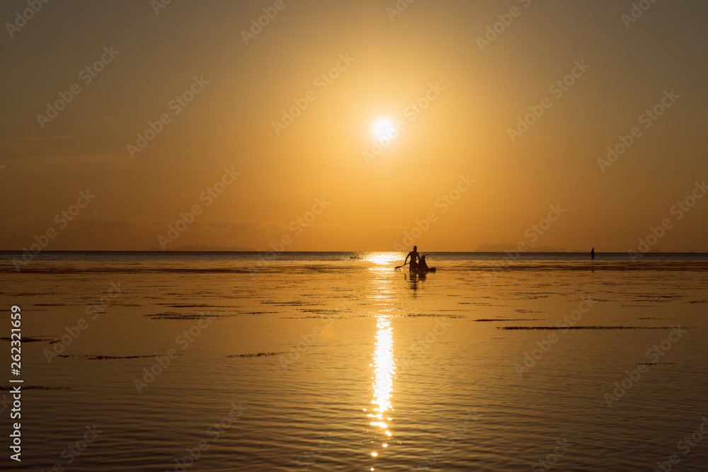 Silhouette of a couple on a boat in the sea at sunset