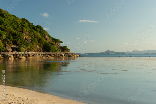 White sandy tropical beach with calm wave and blue lagoon on sunny day