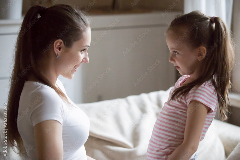 Happy mother looking at smiling daughter holding her hands Happy mother looking at smiling daughter holding her hands