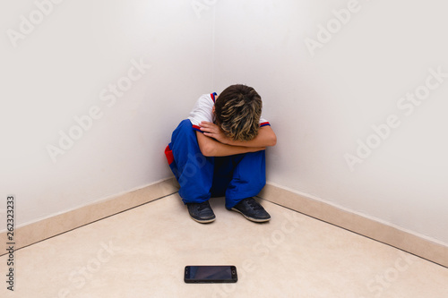concept of cyber bulling. Child in school uniform crying in front of smartphone.
