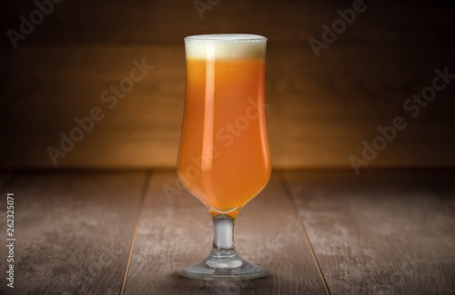 Fotografía Golden unfiltered IPA from craft brewery, hazy juicy tropical beer against wood,