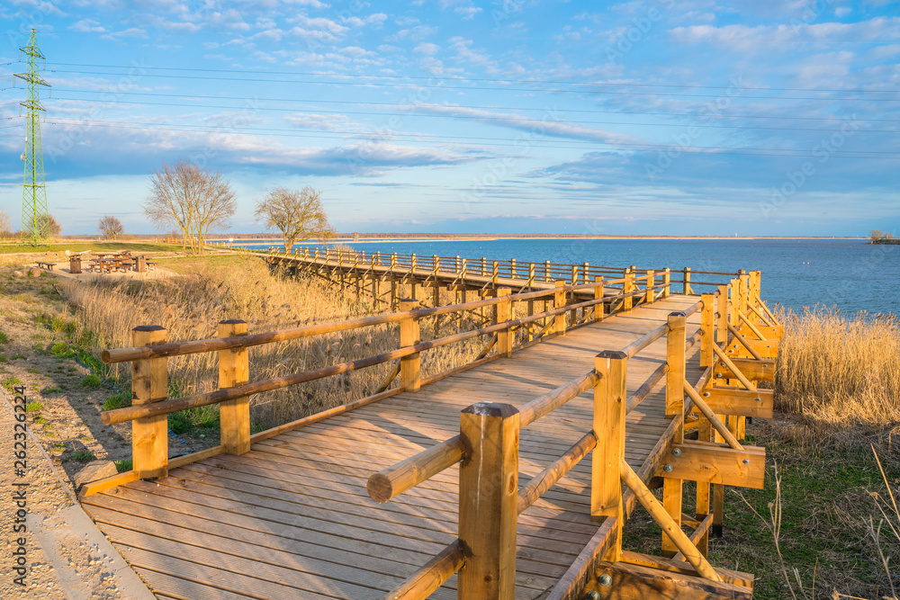 Pedestrian wooden bridge in the park. Place to rest near the lake. View of the park at sunset.