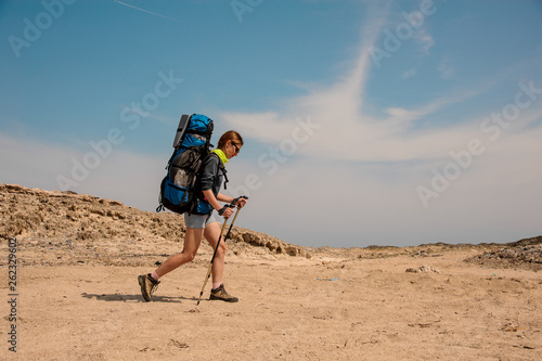 Young girl hiking with walking sticks in desert