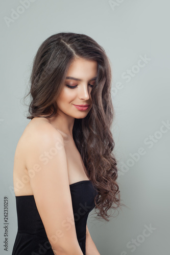 Pretty brunette model woman with long curly brown hair and natural makeup