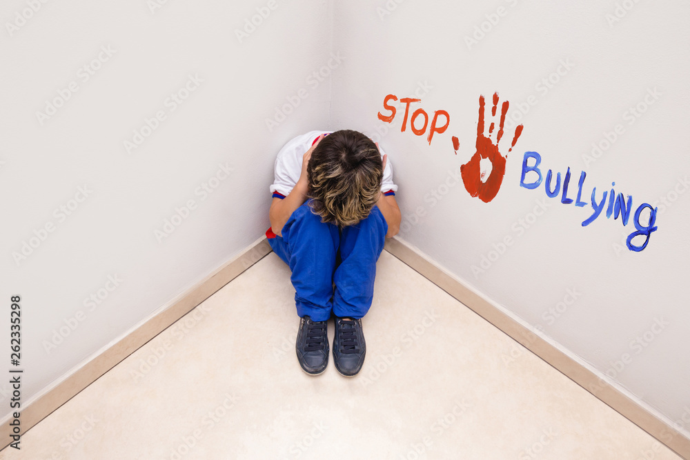 crying child in school uniform and written English text STOP BULLYING