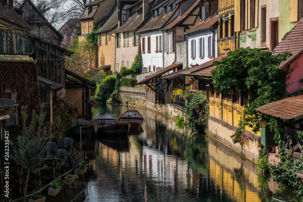 Romantic cityscape. Old houses on the embankment along the canal. There are reflections of houses in the water. Spring morning City of Colmar, Alsace. France.