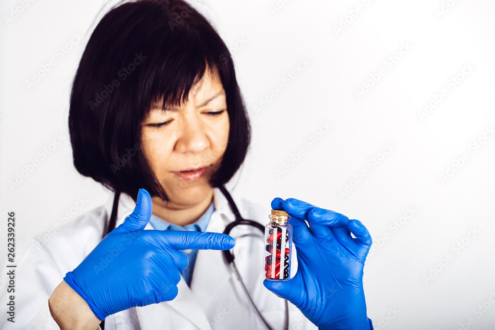 Doctor in medical gloves holding glass bottle with black-red capsules Doctor in medical gloves holding glass bottle with black-red capsules