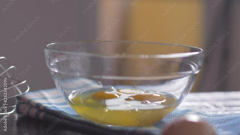 Breaking eggs into a glass bowl Breaking eggs into a glass bowl