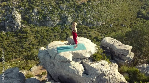 Aerial Footage of Mature Yoga Fitness Woman Resting and Breathing Between Poses, Standing on Cliff Edge of Ravine. Camera Moving Towards and Over Model.