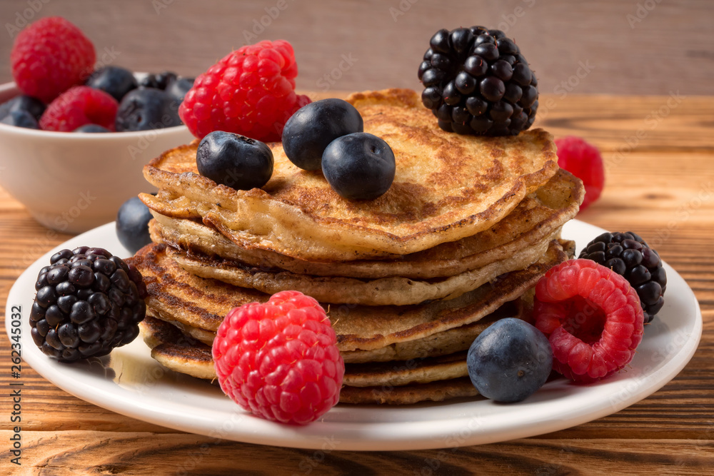 Pancakes with blueberries and strawberries and cup of red juice on wooden background. Close Up. Soft focus. Pancakes with blueberries and strawberries and cup of red juice on wooden background. Close Up. Soft focus.