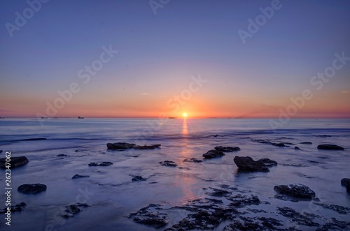 Paesaggio marino con scogli che affiorano dal mare al tramonto