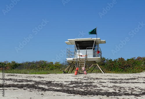 Lifeguard station on Pepper Park beach in Ft. Pierce, Florida on Hutchinson Island flying a green flag signaling it is all clear to swim on a warm sunny day. © Joni
