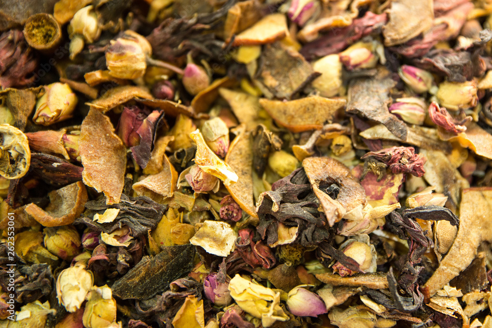 Herbal oriental tea with flower blossom like pink rose, fruit pieces and tea leaves. Close up. 