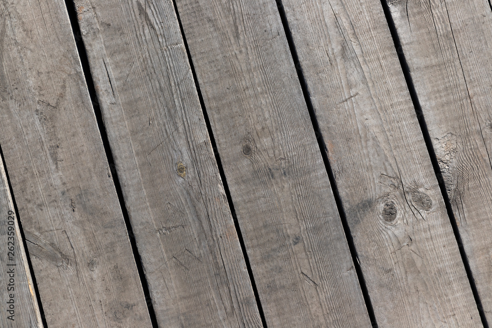 Outdoor wooden flooring from the planks. Knots, scratches and black lines between the boards. Texture for background.