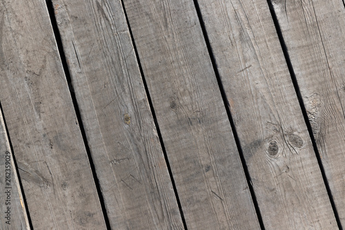 Outdoor wooden flooring from the planks. Knots, scratches and black lines between the boards. Texture for background.