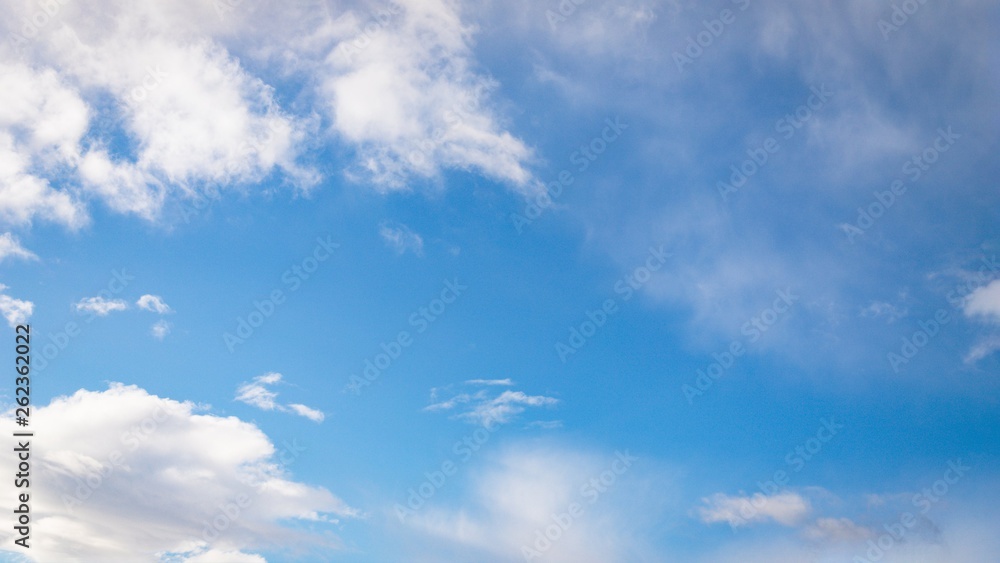 White fluffy and cirrocumulus clouds on a blue sky background. 16:9 panoramic format White fluffy and cirrocumulus clouds on a blue sky background. 16:9 panoramic format