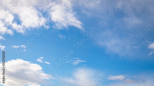 White fluffy and cirrocumulus clouds on a blue sky background. 16:9 panoramic format