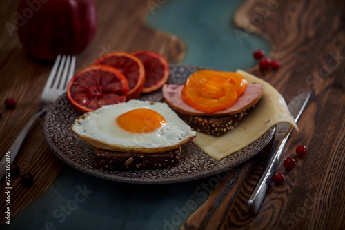 Grain bread with fried egg, tomato, cheese and bacon on ceramic plate with red orange  photo