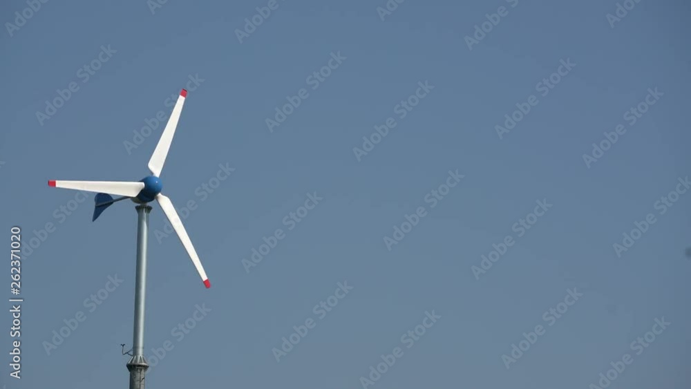 A white pinwheel is spinning under the blue sky. Alternative energy source by wind is important power generation method for human in the future. A white pinwheel is spinning under the blue sky. Alternative energy source by wind is important power generation method for human in the future.