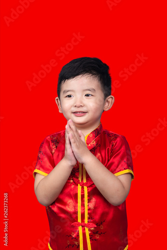 Chinese New Year Concept, Cute Asian boy in red traditional Chinese suit isolated on red with clipping path.