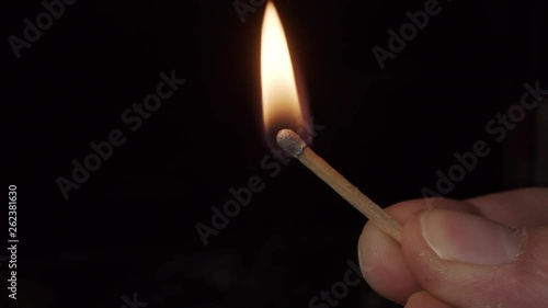 Blue matchstick igniting, burning and fuming in slowmotion on black background