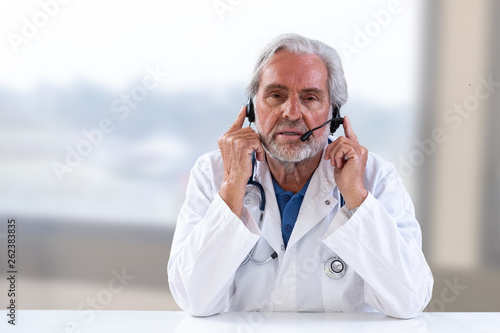 Senior Male doctor listening and discussing,with patient during telemedicine session. photo