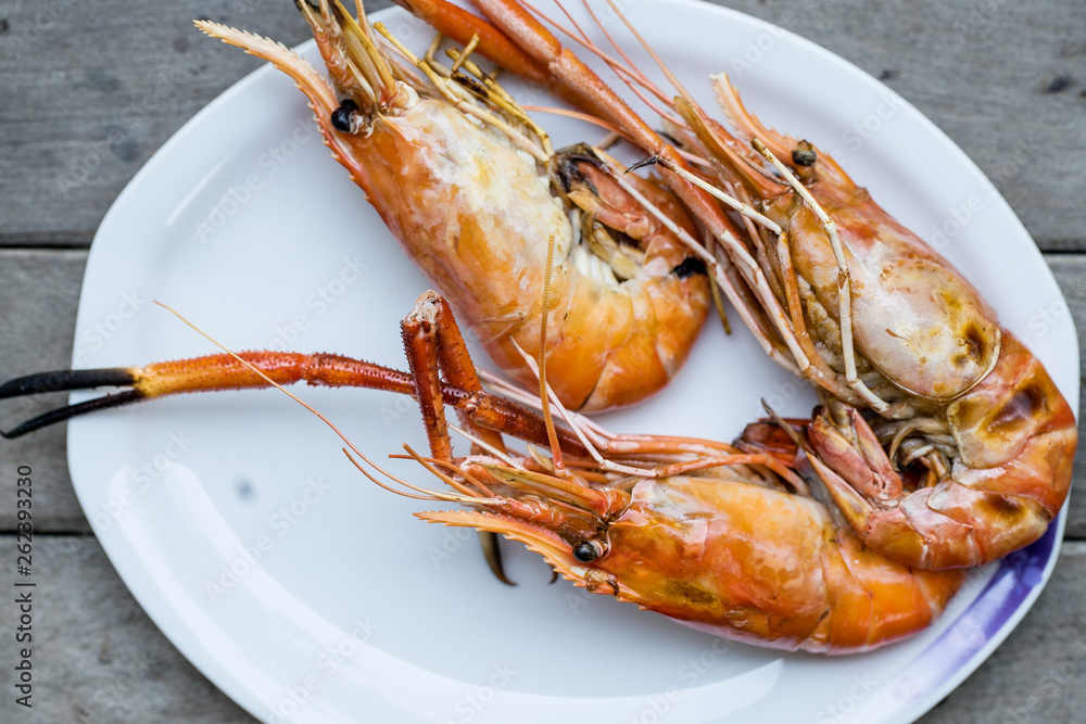 Closeup grilled shrimps on the white plate delicious seafood on the wood table or background Closeup grilled shrimps on the white plate delicious seafood on the wood table or background