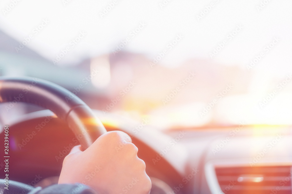 Close up woman hand driving car in sunset.