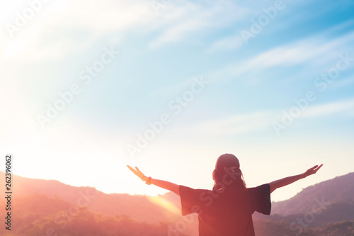 Copy space of woman raise hand up on top of mountain and sunset sky abstract background.