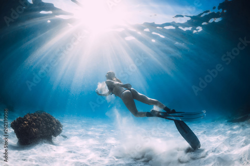 Attractive woman freediver with white sand in hands over sandy sea with fins. Freediving underwater in ocean