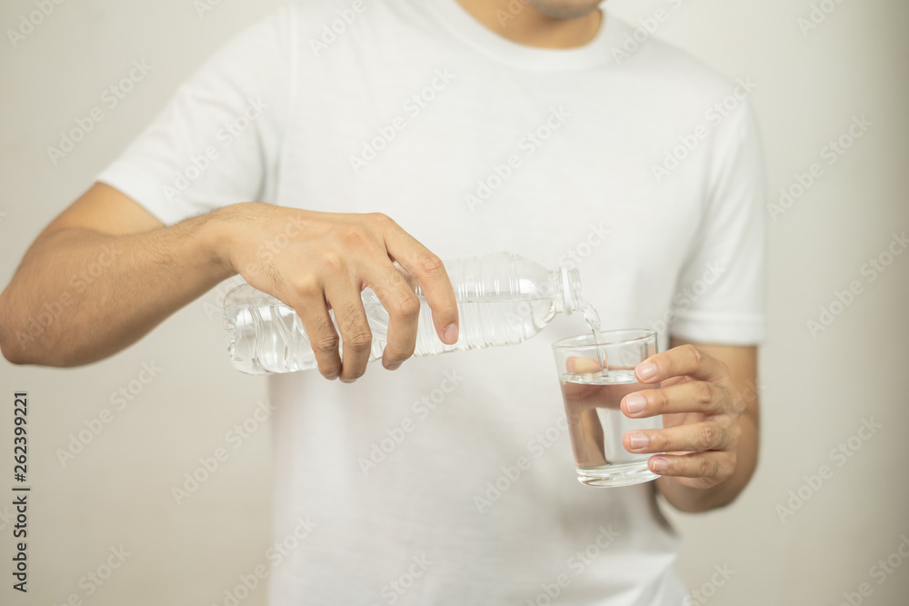 man hand holding a bottle of water Pouring water into a glass. man hand holding a bottle of water Pouring water into a glass.