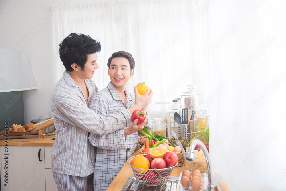 Young asian male homosexual couple cooking in kitchen