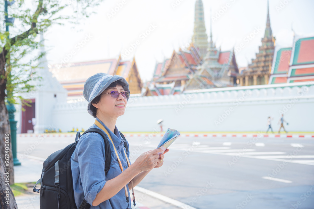 Senior asian woman tourist holding a paper map traveling in Bangkok,Thailand.