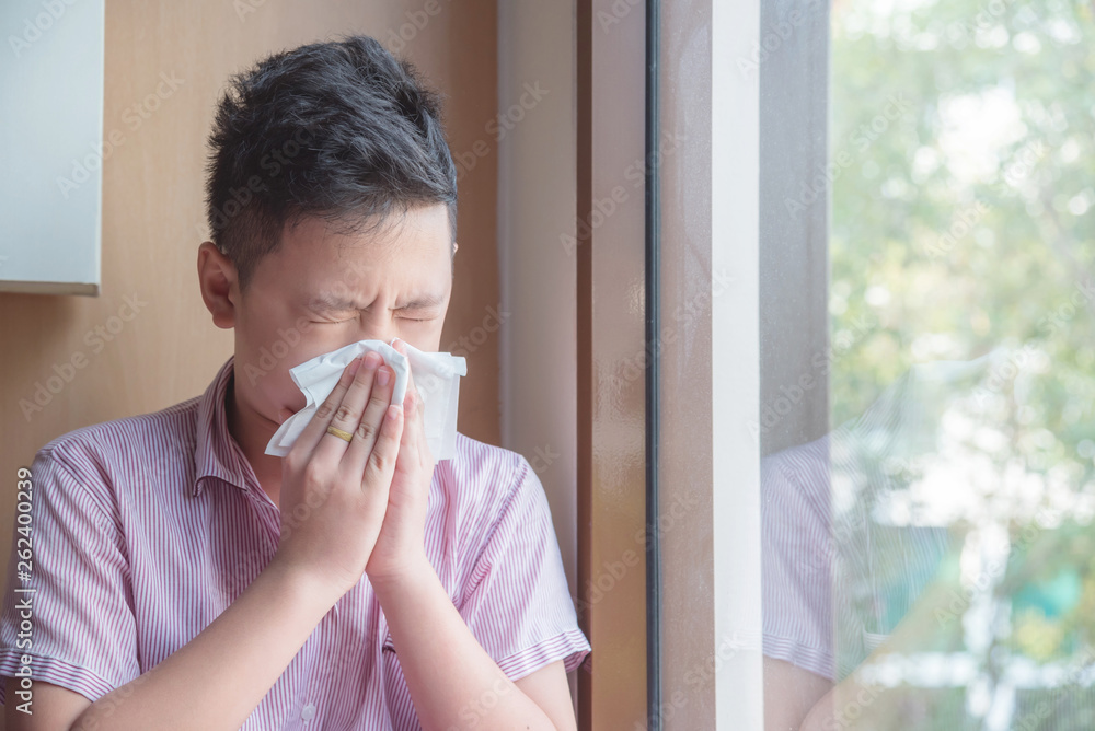 Φωτογραφία Sick asian boy blowing nose into tissue, Unhealthy child suffering from running nose or sneezing and covering his nose and mouth by tissue paper