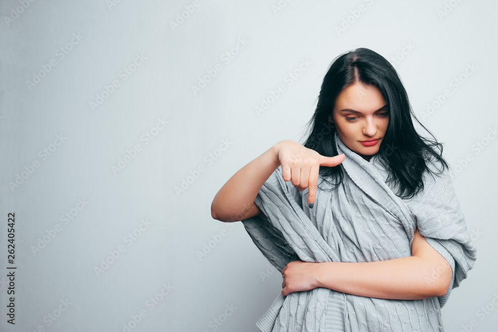 Beautiful brunette girl looks down and points there with a finger. Beautiful brunette girl looks down and points there with a finger.