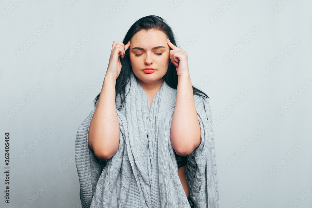 Beautiful pensive girl brunette rubs her temples with fingers, is experiencing a headache, tension, stress. Beautiful pensive girl brunette rubs her temples with fingers, is experiencing a headache, tension, stress.