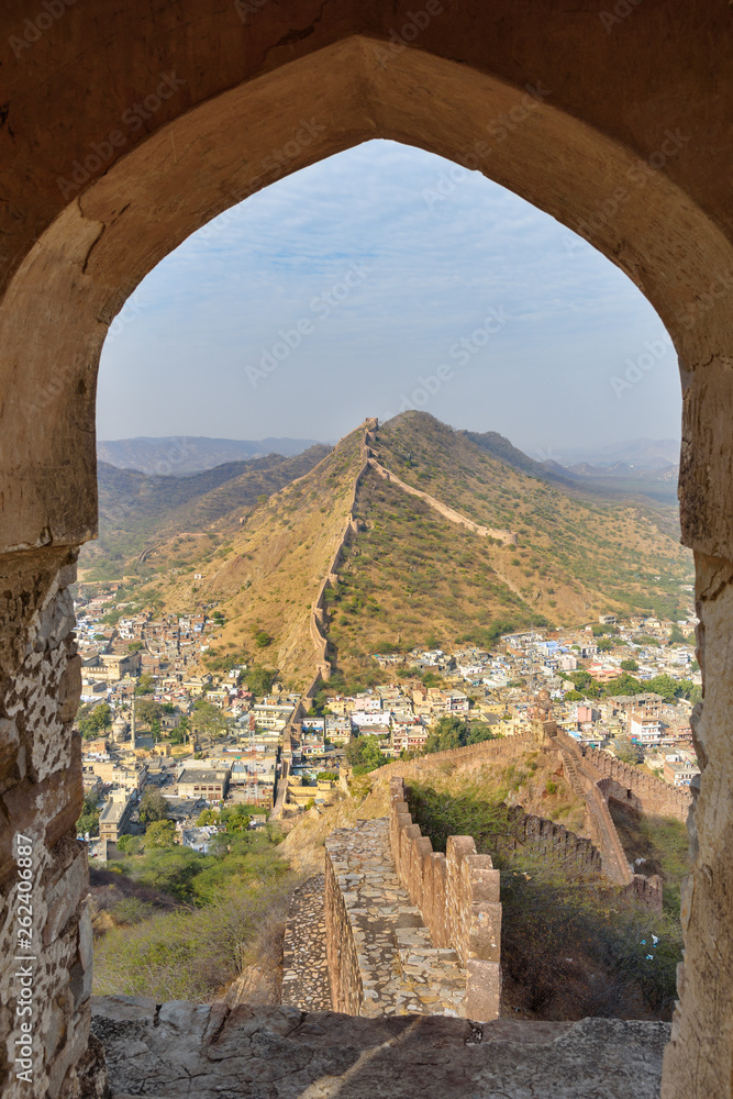 Ancient long wall with towers around Amber Fort through the arch of tower walls. Rajasthan. India