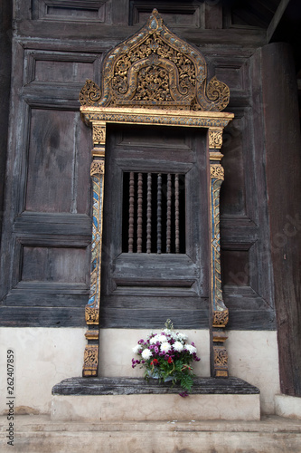 Chiang Mai Thailand, decorated window frame at Wat Phan Tao with flower offering on steps photo