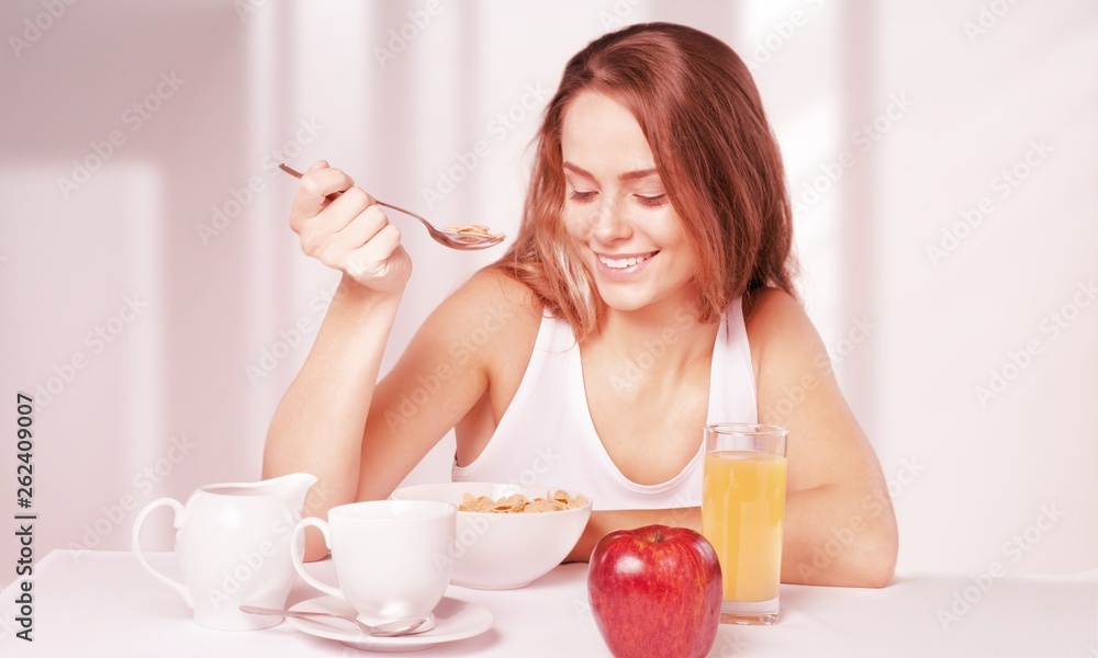 Attracive young woman enjoying tea and fruits on breakfast