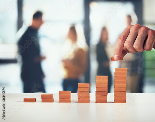 Businessman puts a brick on a bricks pile. Concept of growing statistics and success