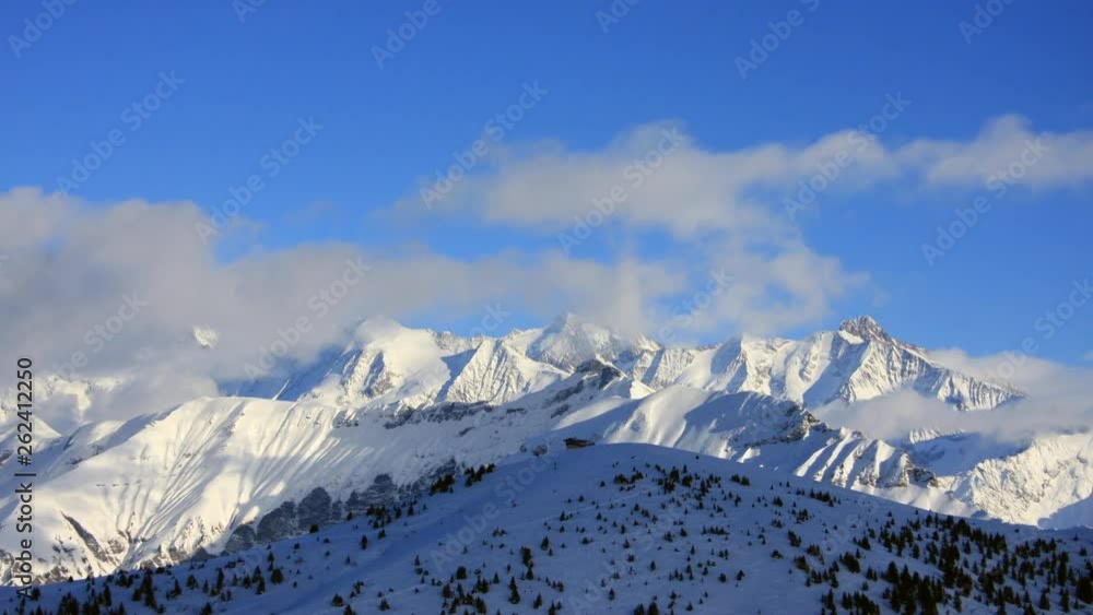 Timelapse showing cloud moving over mountain peaks in the Mont Blanc area of the French Alps in winter, with blue sky. Timelapse showing cloud moving over mountain peaks in the Mont Blanc area of the French Alps in winter, with blue sky.
