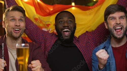 Sports fans with Spanish flag cheering for national team, watching game in pub
