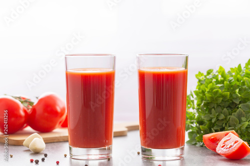 Tomato juice with basil and spices. Glasses with tomato juice and fresh tomatoes.